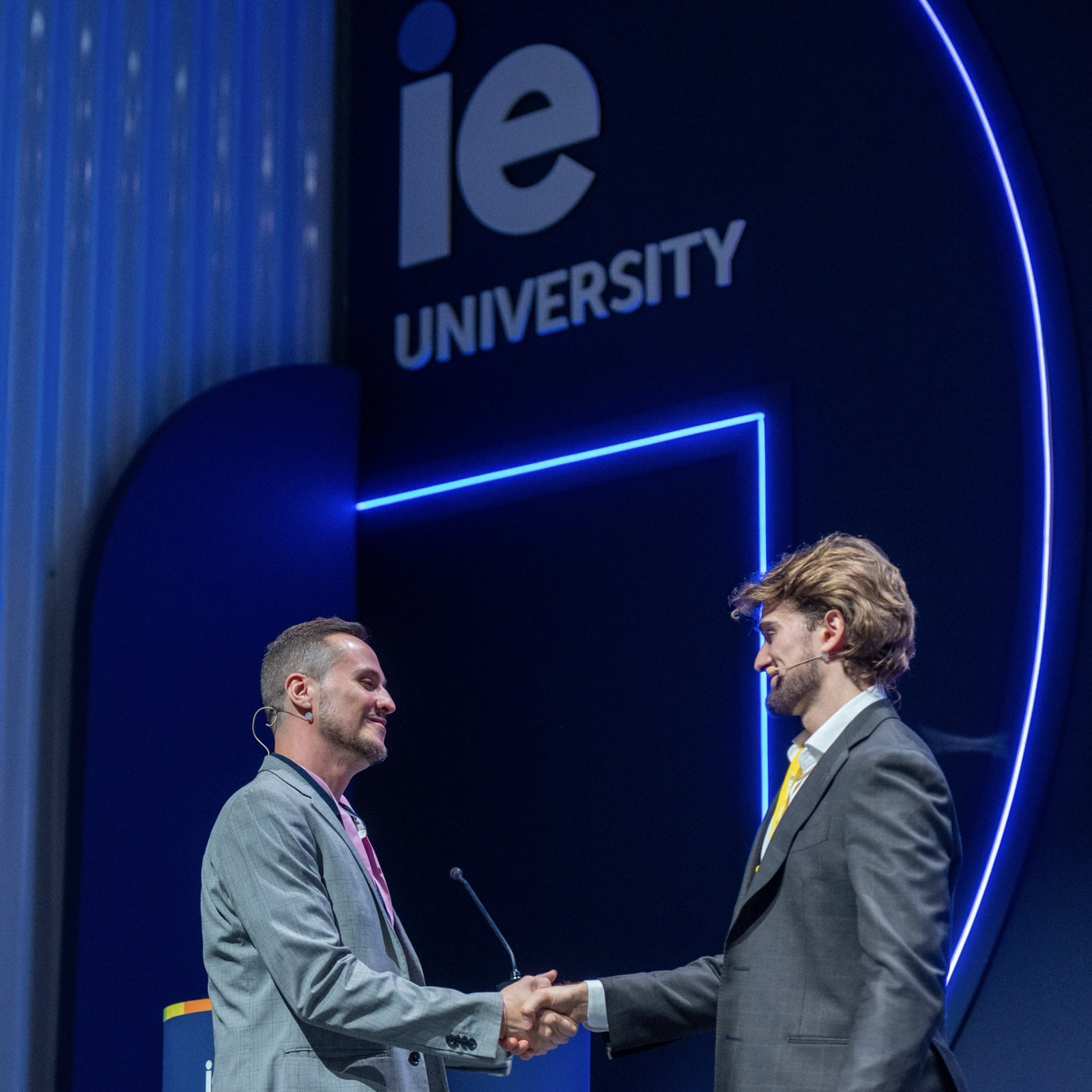 Dalton Kern and Thiago Ferreira shaking hands on stage at IE University after the panel